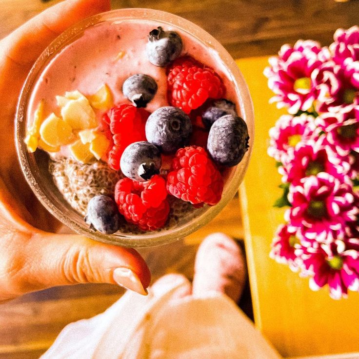 a person holding a bowl of food with berries and lemons