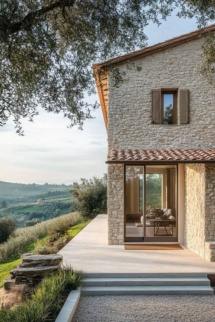 an outdoor patio with stone walls and steps leading up to the house