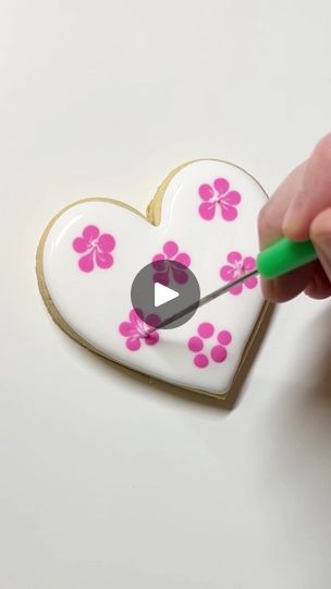 someone is decorating a heart with flowers and a green marker in the shape of a flower