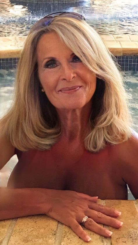 an older woman sitting in front of a swimming pool with her hands on the edge