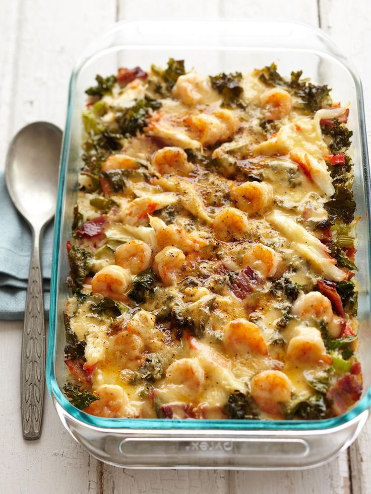 a casserole dish with shrimp, broccoli and cheese in it next to a spoon