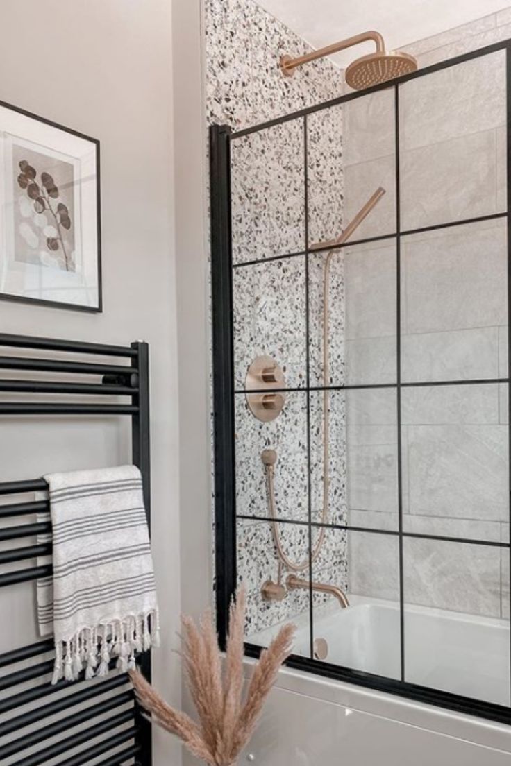 a bathroom with a shower, towel rack and bathtub next to the wall is decorated in black and white