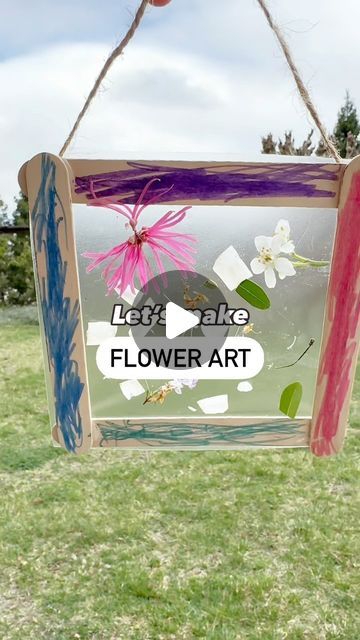 a sign that says let's take flower art hanging from a rope in the grass