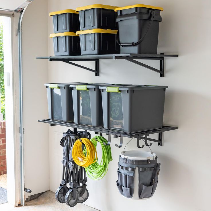 there are several storage bins on the wall with hoses and buckets hanging from it