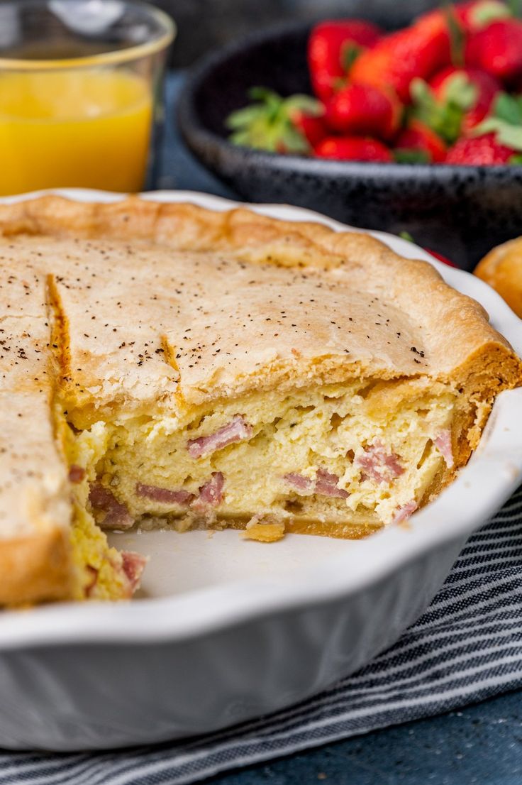 a close up of a pie on a plate with strawberries and orange juice in the background