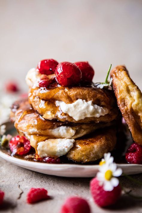 a stack of pancakes with whipped cream and raspberries