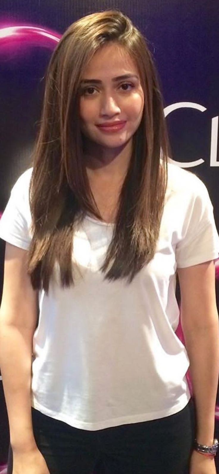 a woman with long hair standing in front of a sign