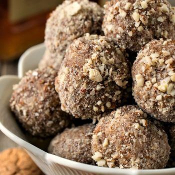 a white bowl filled with chocolate covered donuts next to cookies and nuts on a table