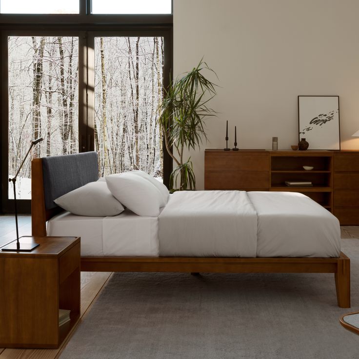 a bed with white sheets and pillows in a room next to a large glass window