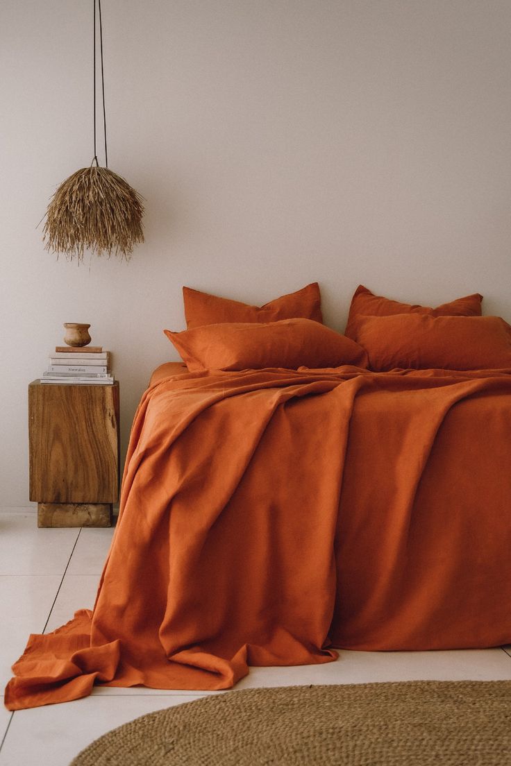 an orange comforter on a bed in a room with white walls and flooring