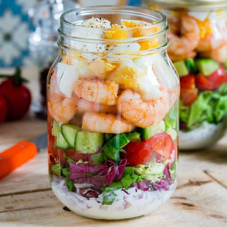 two mason jars filled with salad and shrimp