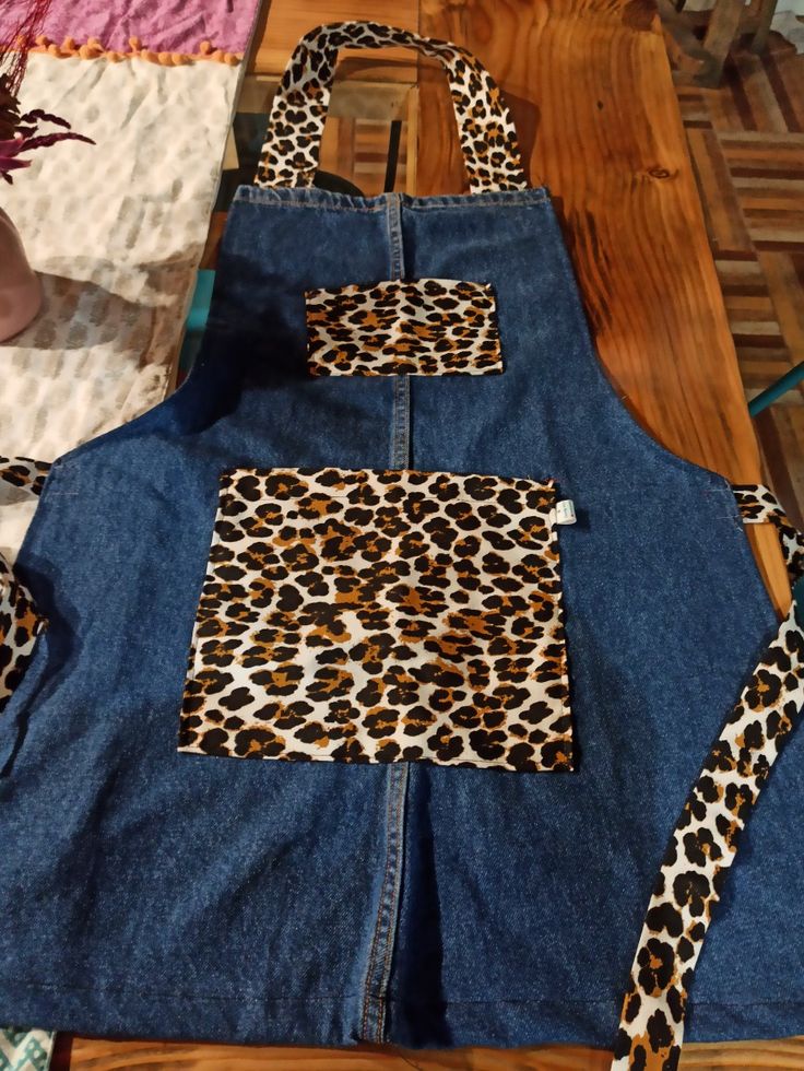 an apron made out of jeans with leopard print on the front and back, sitting on top of a wooden table