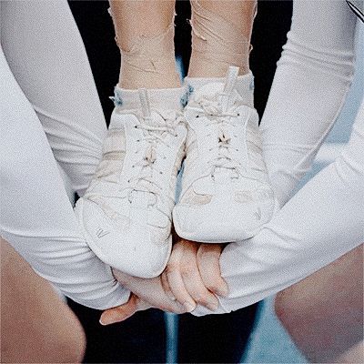 two people holding hands with white shoes on top of each other's feet and their arms wrapped around them