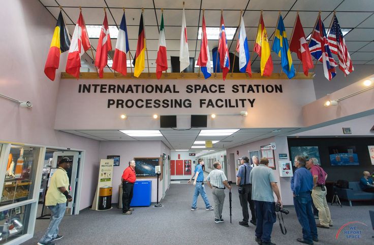 people are walking through the international space station processing facility with flags hanging from the ceiling