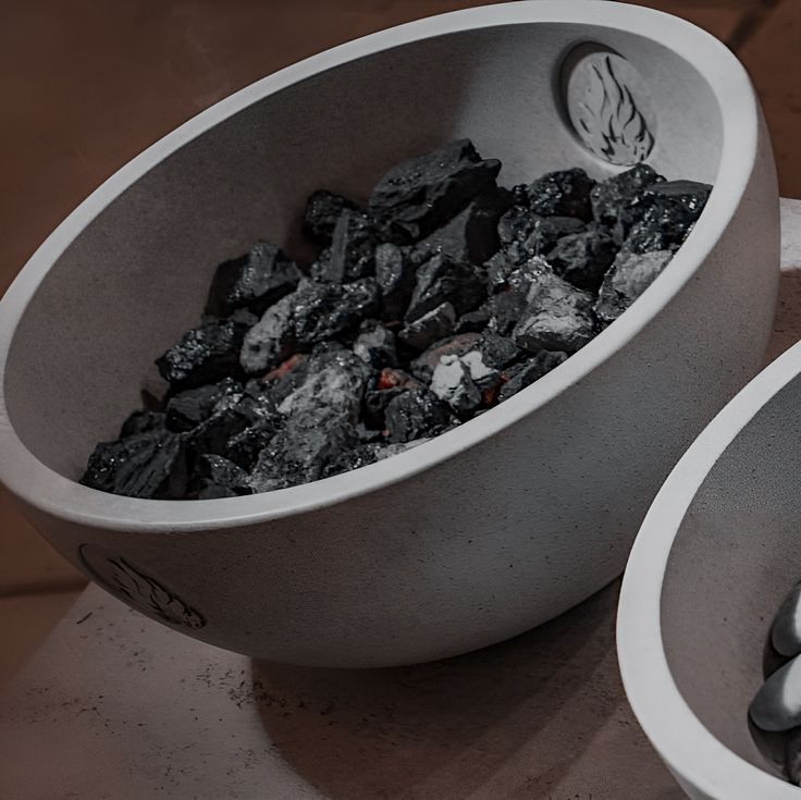 two white bowls filled with coal on top of a table