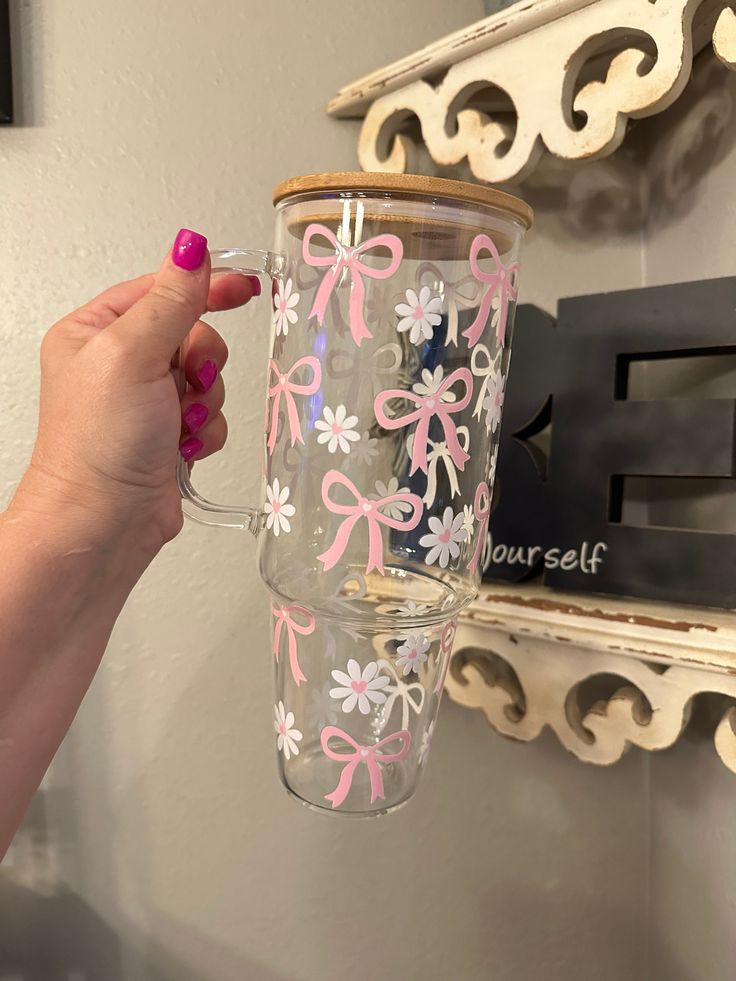 a woman holding up a cup with pink bows on the inside and white flowers on the outside