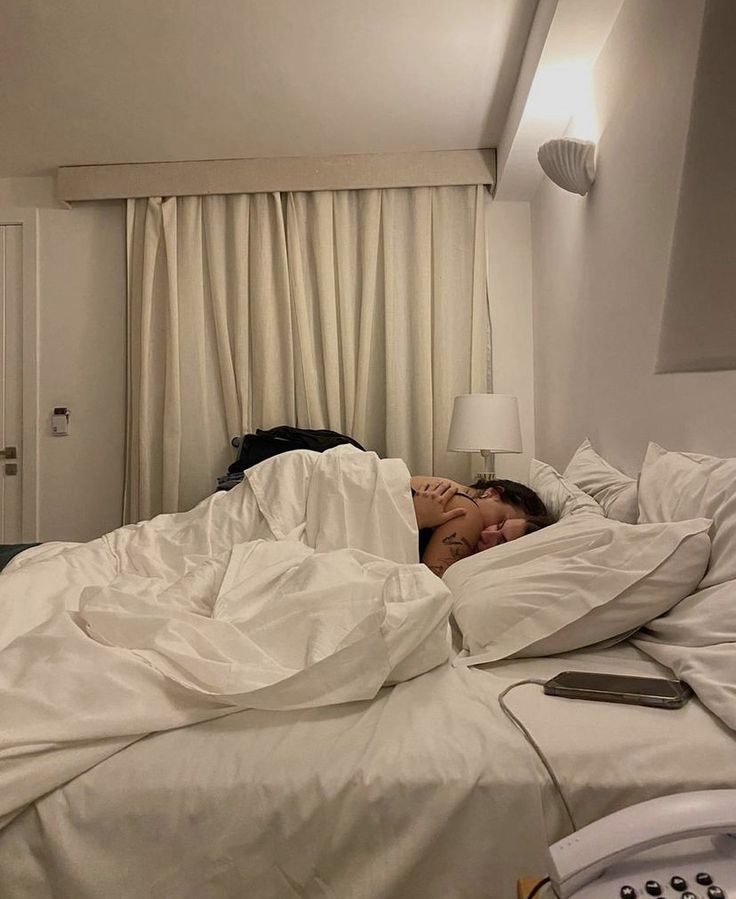 a woman laying in bed with white sheets