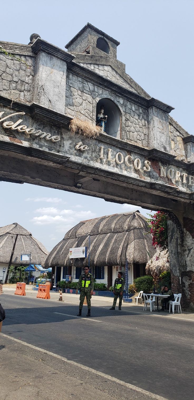 two men standing under an overpass with thatched umbrellas