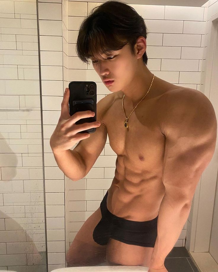 a shirtless man taking a selfie in the bathroom mirror with his cell phone