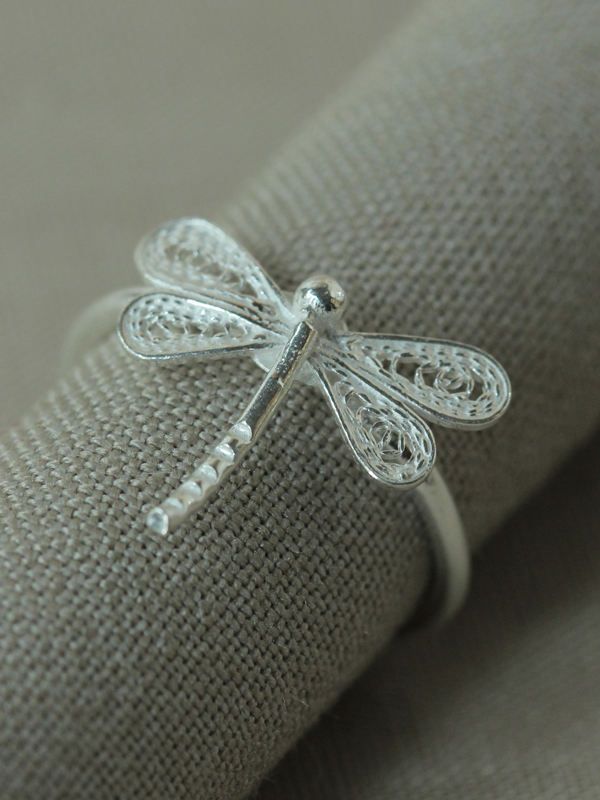 a dragonfly ring sitting on top of a piece of cloth next to a pillow