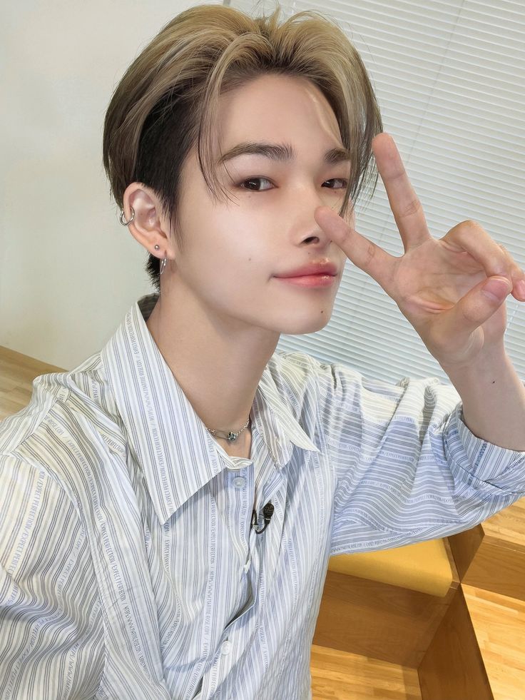 a young man making the peace sign with his hand while sitting at a wooden table