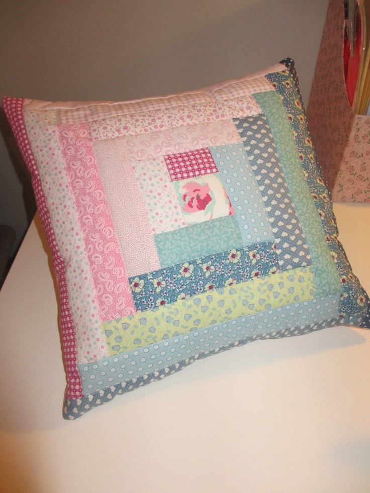 a decorative pillow made from patchwork material on a table with a lamp in the background