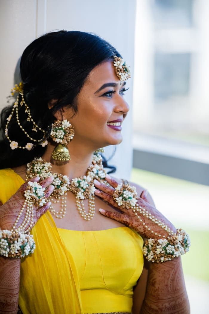 a woman in a yellow dress with jewelry on her neck and hands around her chest