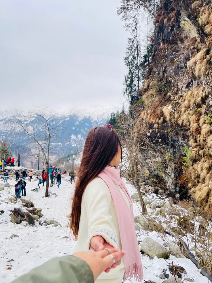 a woman holding the hand of a man on top of a snow covered mountain