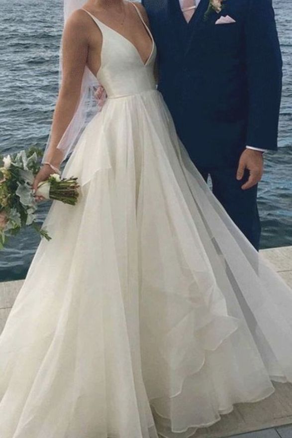 a bride and groom standing next to each other in front of the water at their wedding