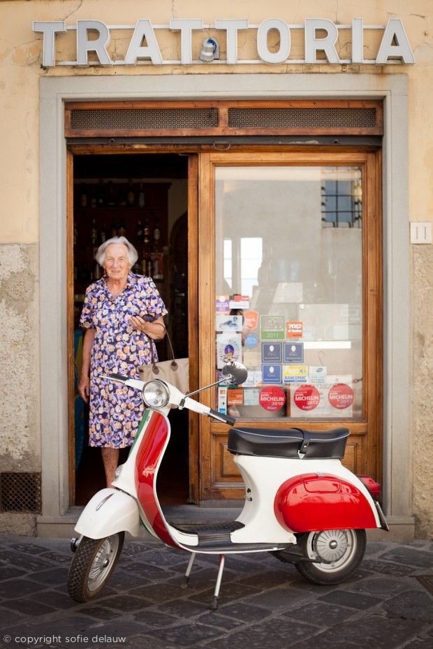 an older woman standing next to a scooter parked in front of a store