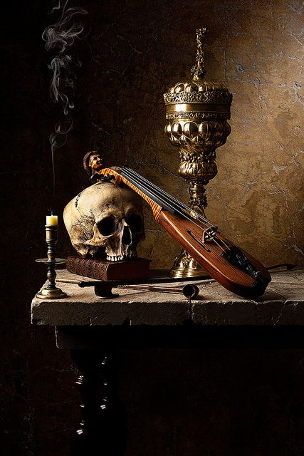 a still life with a violin, skull and candlestick on a table next to a candle holder