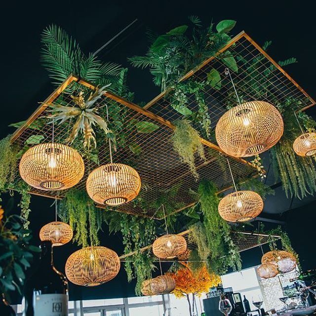 hanging plants and wicker baskets decorate the ceiling at an outdoor venue with greenery