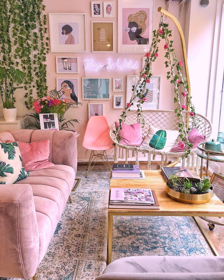 a living room filled with pink furniture and lots of plants on the wall behind it