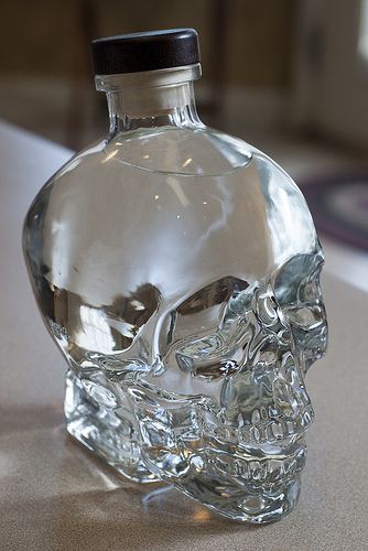 a clear glass skull bottle sitting on top of a table