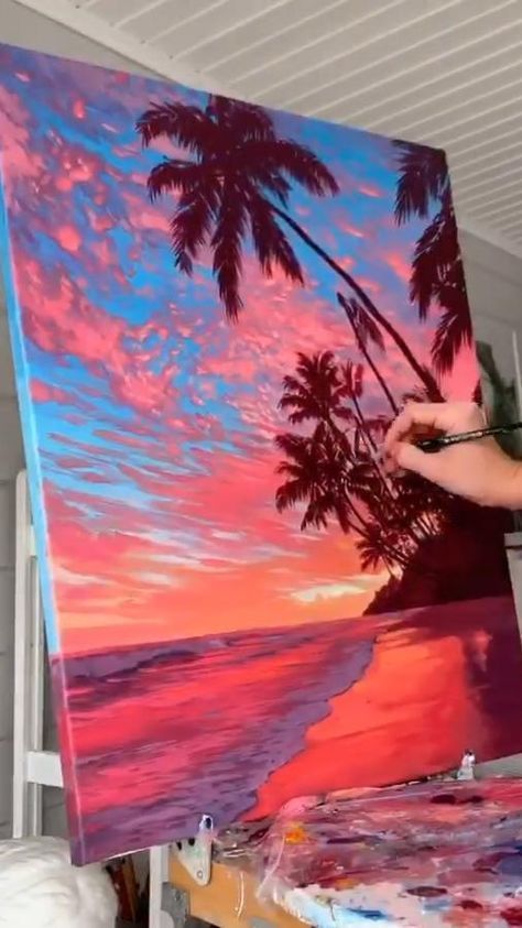 a person is painting on an easel with palm trees in the background at sunset