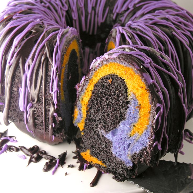 a chocolate cake with purple icing and sprinkles on the top is cut in half