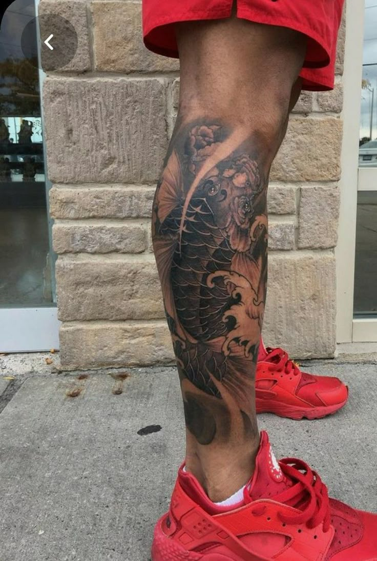 a man's leg with a dragon tattoo and red sneakers on the sidewalk in front of a brick building