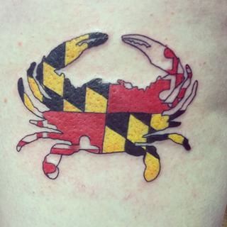 a crab tattoo on the back of a person's leg with yellow and black stripes