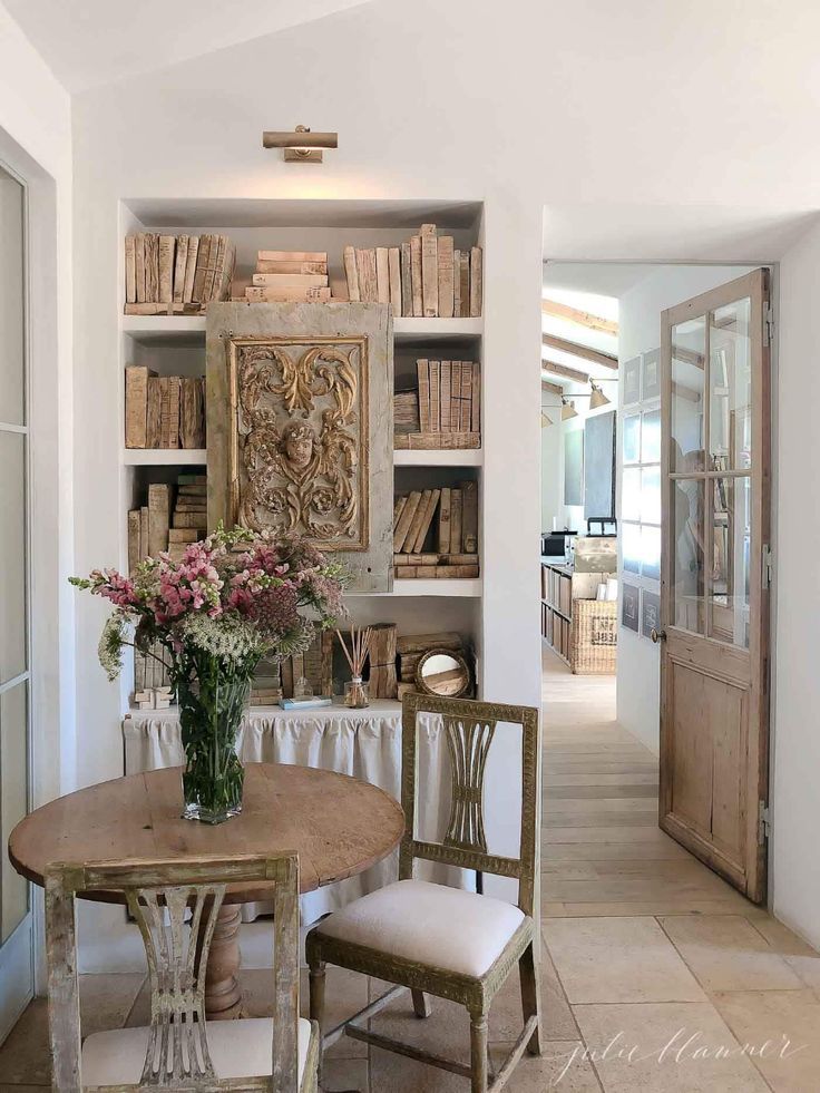 a dining room table and chairs with bookshelves in the background