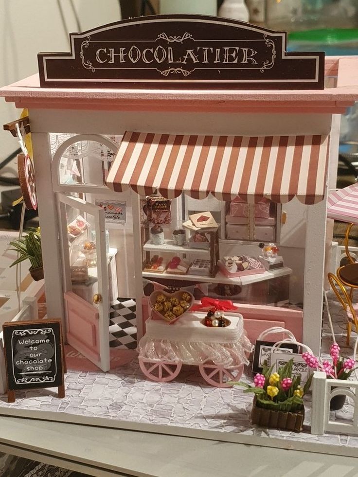 a miniature model of a chocolate shop with pink and white stripes on the awning