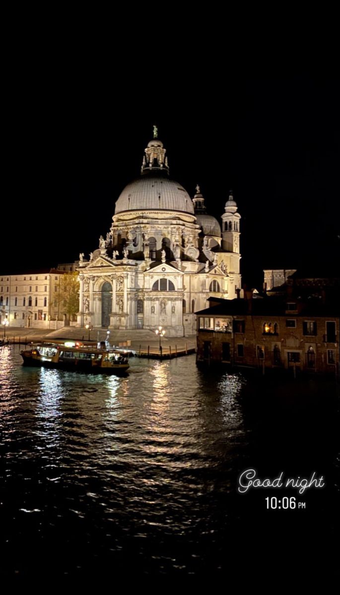 a large building sitting on top of a river next to a boat in the water