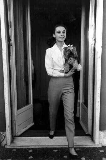 a woman standing in an open doorway holding a cat