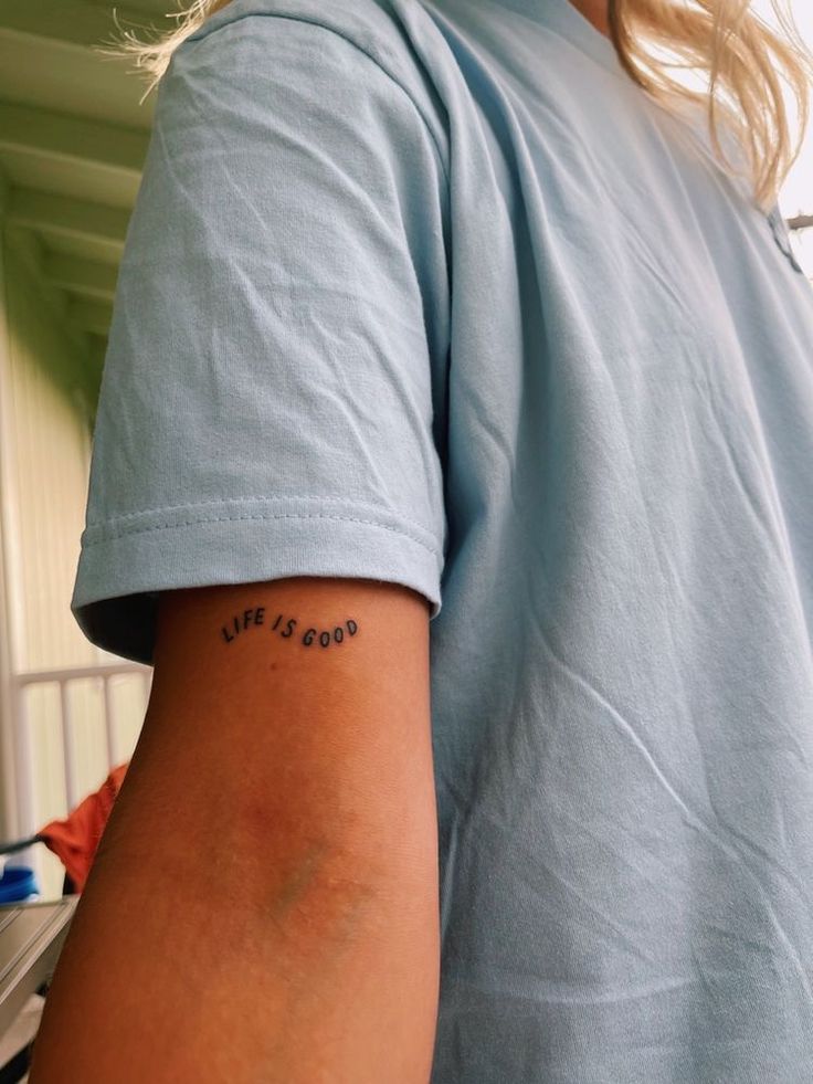 a woman with a tattoo on her arm saying life is good in front of her