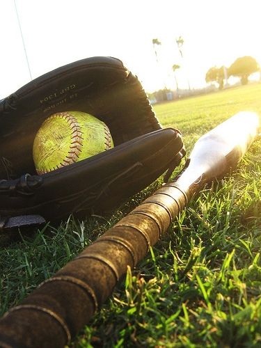 a baseball bat, glove and ball sitting in the grass