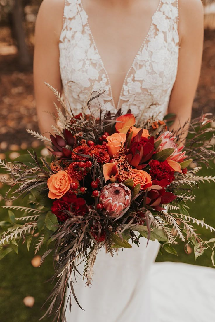 a woman holding a bouquet of flowers in her hands and wearing a wedding dress with an open back