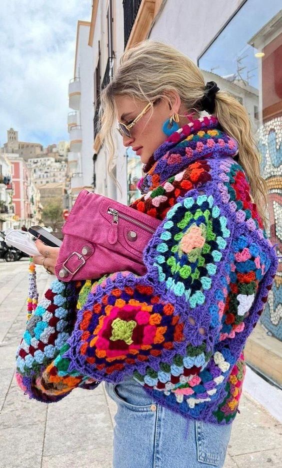 a woman is walking down the street with her purse and cell phone in her hand