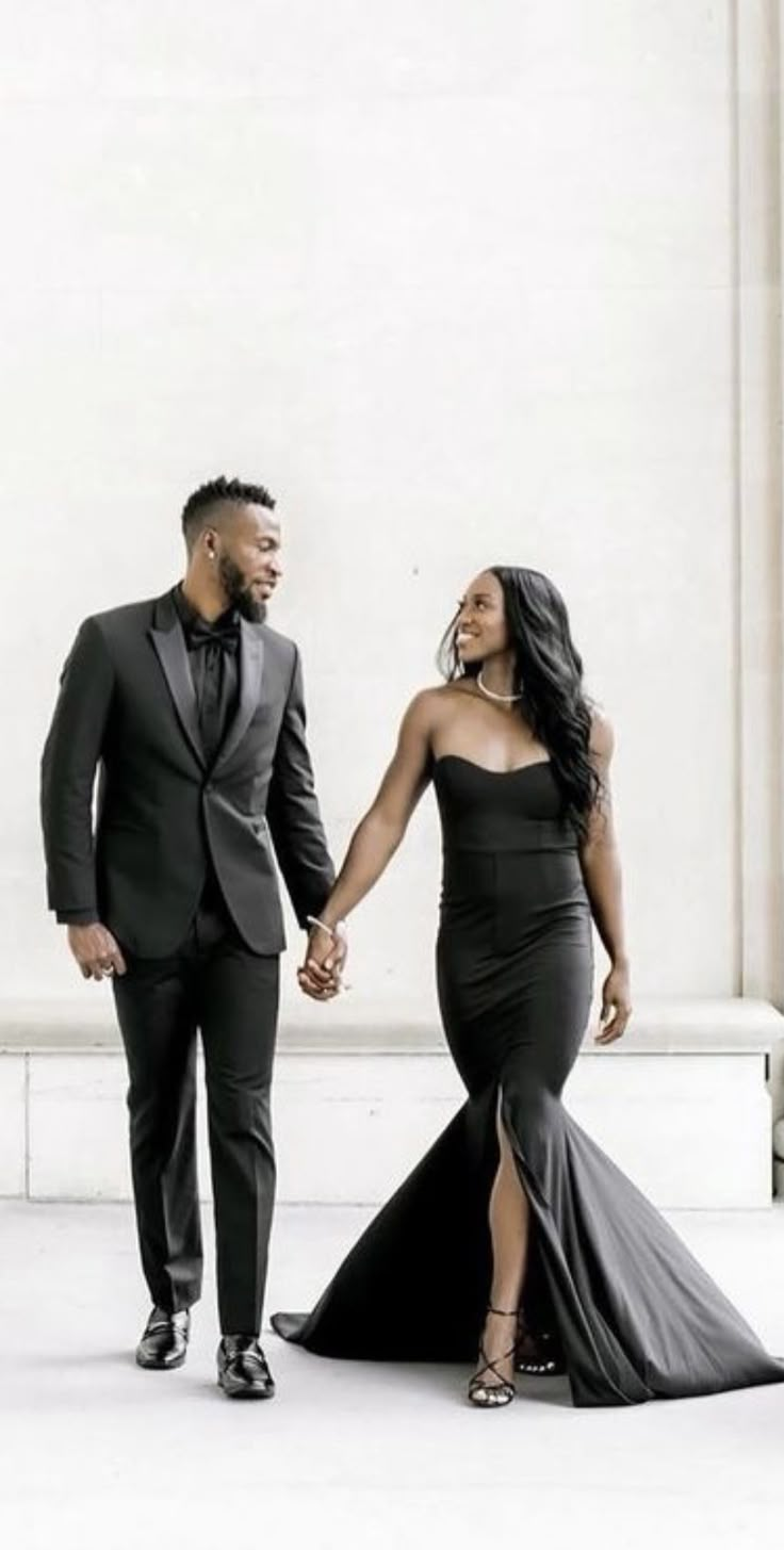 a man and woman in formal wear holding hands