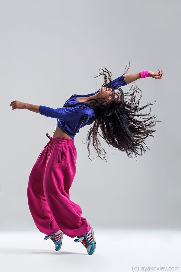 a young woman dancing in the air with her hair blowing back and legs spread out