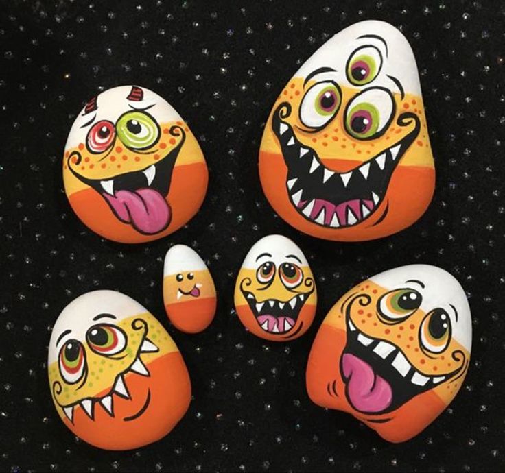 five painted rocks with different faces and mouths, all on top of each other in the shape of an egg