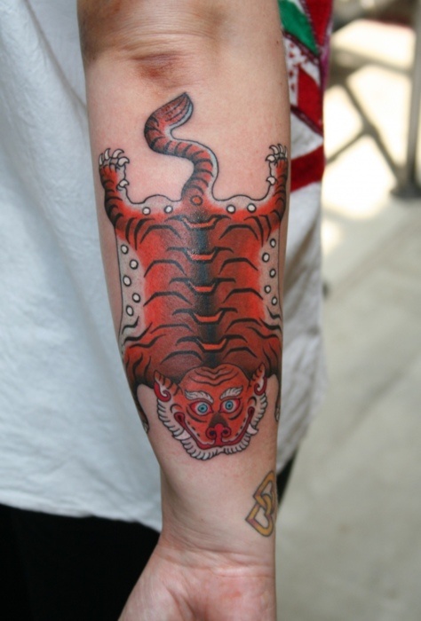 a person with a tattoo on their arm that has a red and black tiger on it